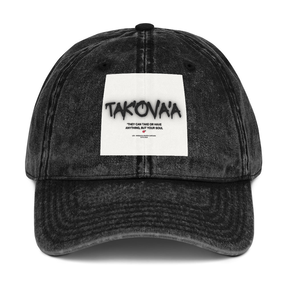 Black denim cap with a white patch featuring text on a white background