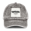 Gray denim cap with a white patch featuring text on a white background