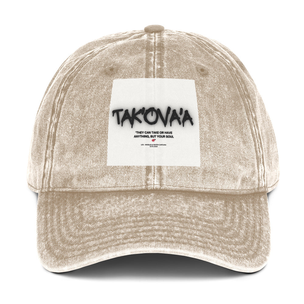 Beige cap with a white patch featuring 'Tak'ova'a' text on a white background